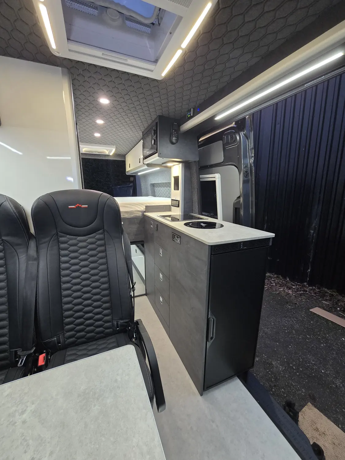 Slate Grey concrete-effect kitchen pod behind the seats in a finished build