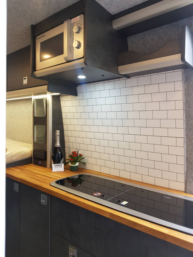 A microwave in its overhead shelf above a kitchen worktop